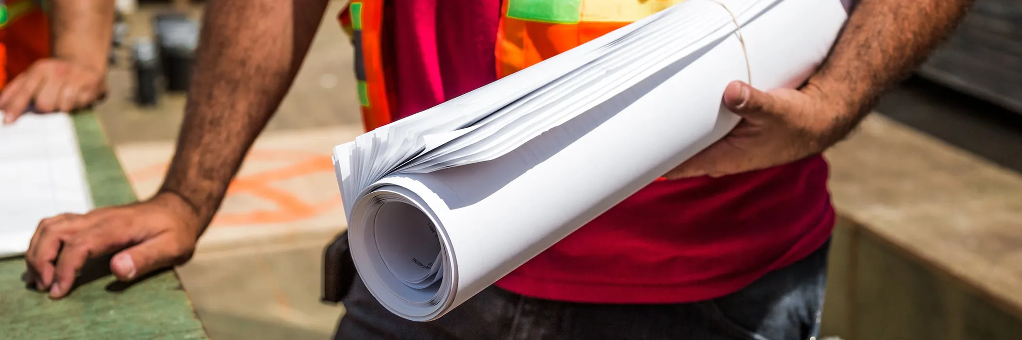 references-min construction worker holding roll of blueprints